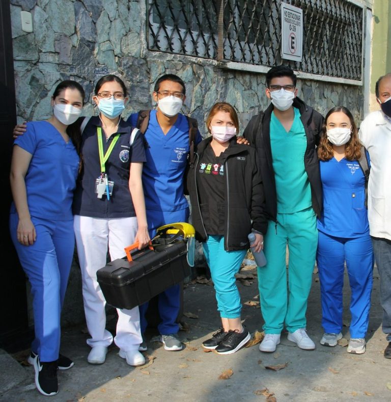 A group of healthcare professionals in masks, standing together outside.